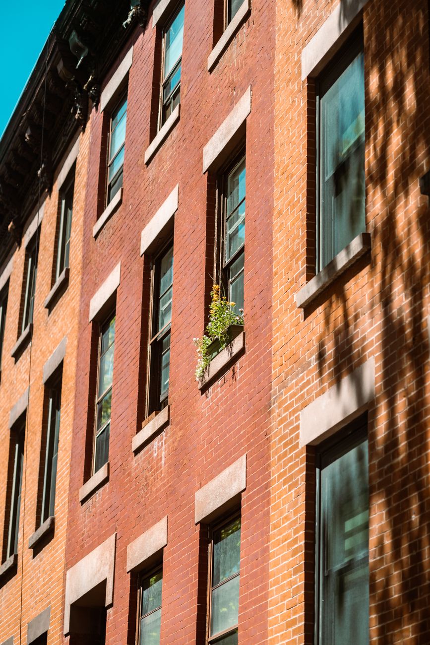 En høj facade i røde mursten med rækker af vinduer